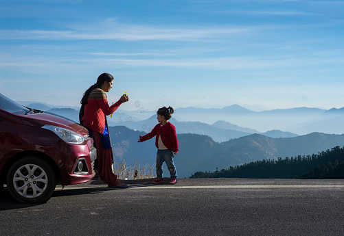 Mother and daughter enjoying the road trip and winter vacation. Car travel vacation concept photo against Himalayan mountain in the background.