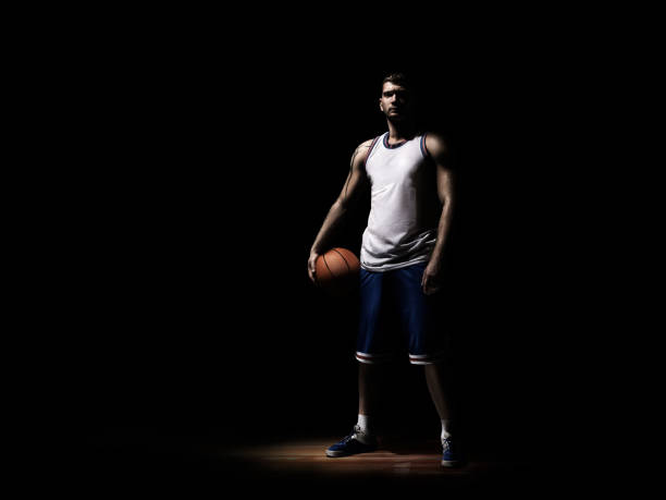 istock basketball player standing in durkness on parquet with ball 640136098