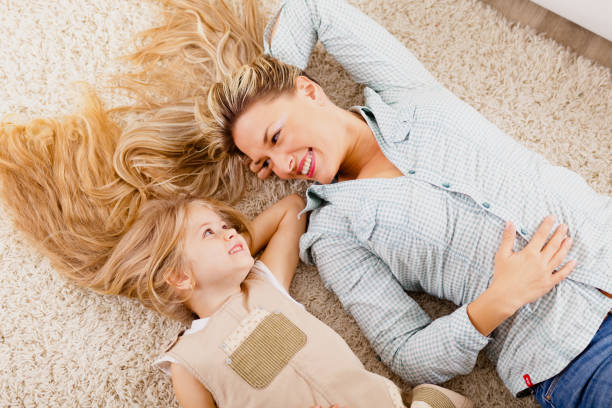 mother and daughter lying on carpet and relaxing - offspring child lying on back parent imagens e fotografias de stock