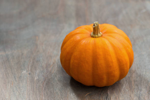istock orange pumpkin on a grey wooden background, top view 640139338
