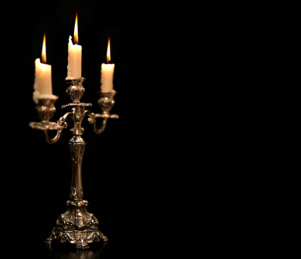 burning old candle vintage Silver bronze candlestick. Isolated Black Background. stock photo