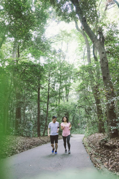istock Cheerful Japanese couple running outdoors in a park 640144088