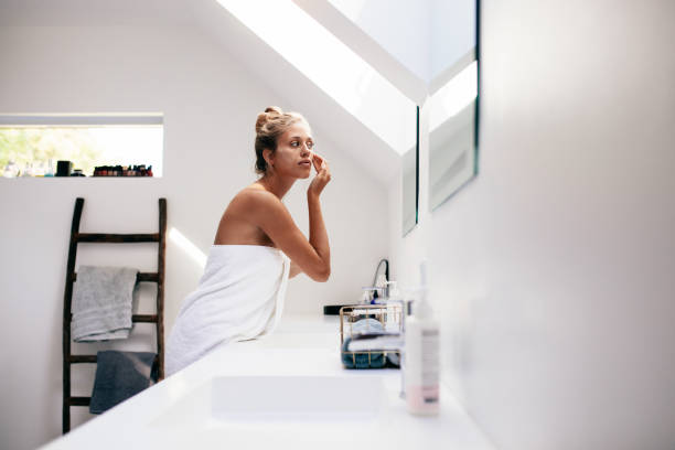 istock Young woman applying cream on her face in bathroom 640146216