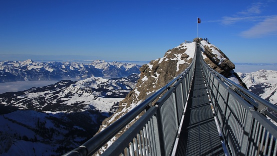 Winter scene in the Swiss Alps. Suspension bridge connecting two mountain peaks on 3000m altitude. View from the Glacier de Diablerets ski area.