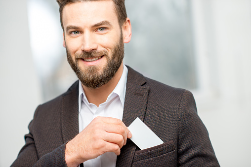 Elegant man in the suit putting business card into the pocket. White card to copy paste