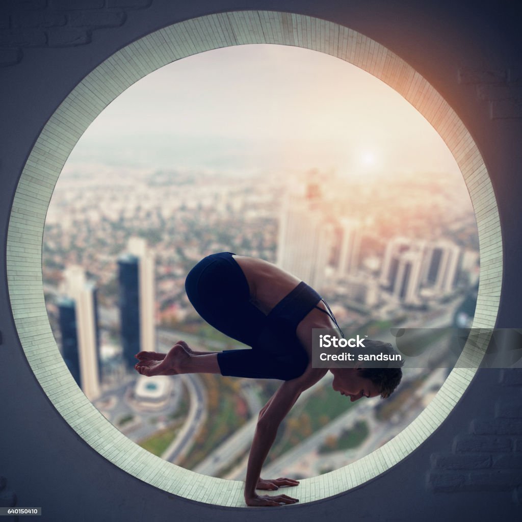 young woman doing yoga young woman doing bakasana in the round window 20-29 Years Stock Photo