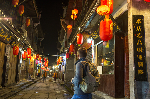 Young traveler man in an alley of the ancient village of fenghuang, China.
