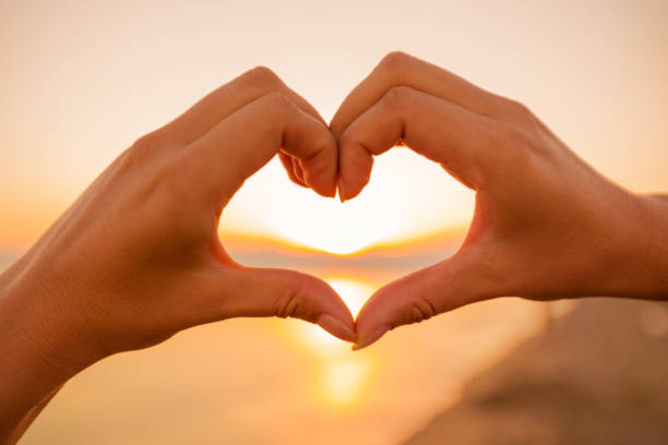 istock Silhouette of hands forming a heart around the sun 640154424