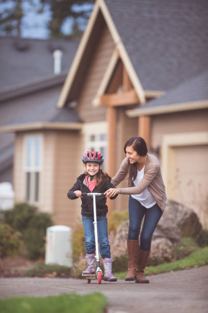 istock Ethnic girl riding scooter with help from her mother 640157110