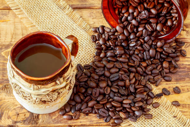 tazza di caffè nero e fagioli su sfondo legno. - coffeetree foto e immagini stock