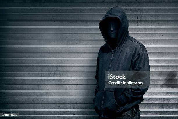 Anonymous Man On Grey Shutter Door Stock Photo - Download Image Now - Mask - Disguise, Protective Face Mask, Spooky