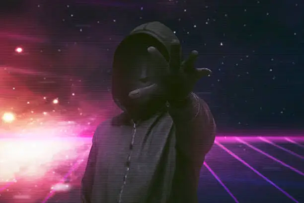 Hooded man with vendetta mask grabbing something over visual background