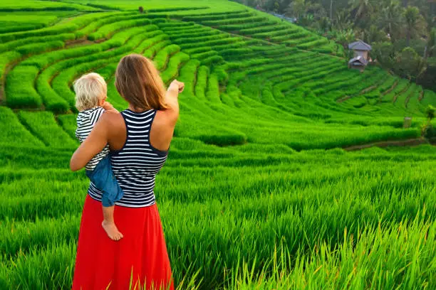 Photo of Mother with child walk on green rice terrace. Bali