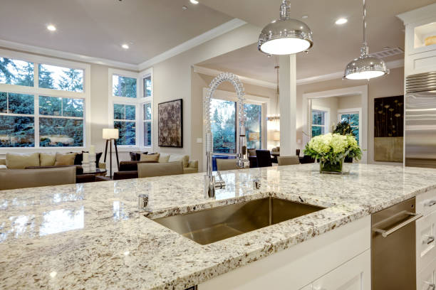 White kitchen design in new luxurious home White kitchen design features large bar style kitchen island with granite countertop illuminated by modern pendant lights. Northwest, USA granite rock stock pictures, royalty-free photos & images