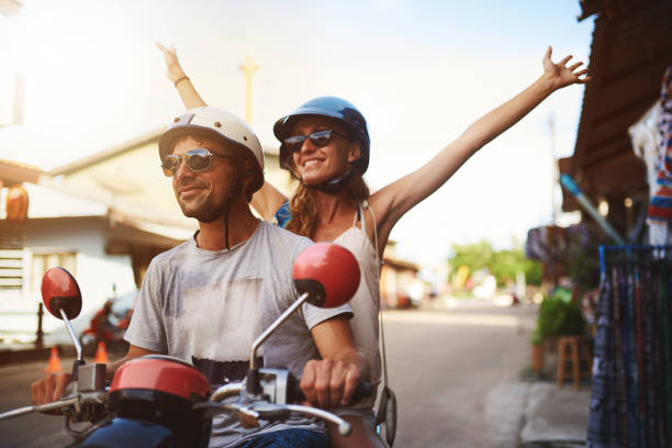 Simply enjoy the ride Shot of young tourists enjoying a scooter ride around the city motor scooter stock pictures, royalty-free photos & images