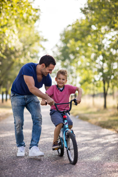istock Happy boy learning to ride bicycle with help of father. 640185682