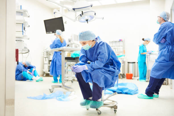 операционная комната полна усталых хирургов - doctor tired protective workwear sadness стоковые фото и изображения