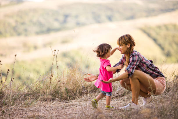 istock Small daughter running into mother's arms in the park. 640187192