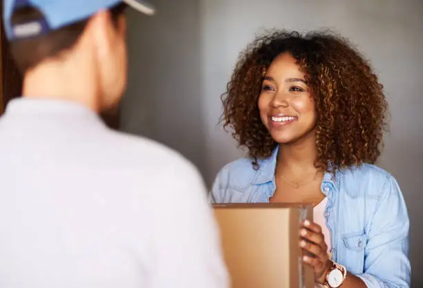 Cropped shot of a woman receiving her package from the delivery man