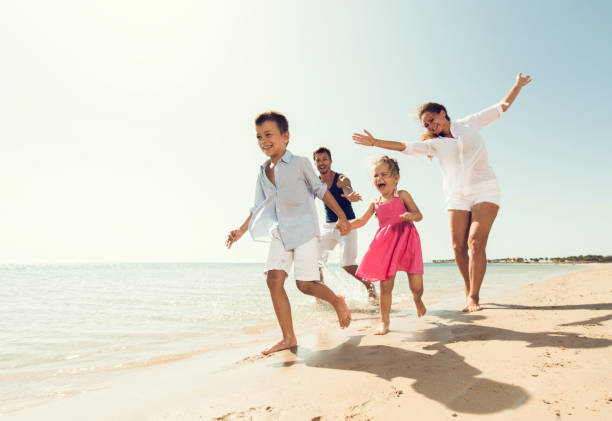 istock Playful parents chasing their kids on the beach. 640190784