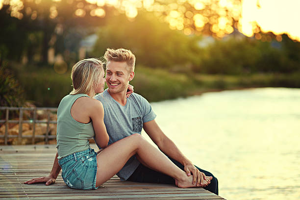 Shot of an affectionate young couple sitting together at a lake outside