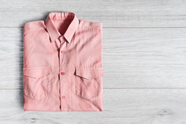 Pink cotton shirt folded on white wooden background