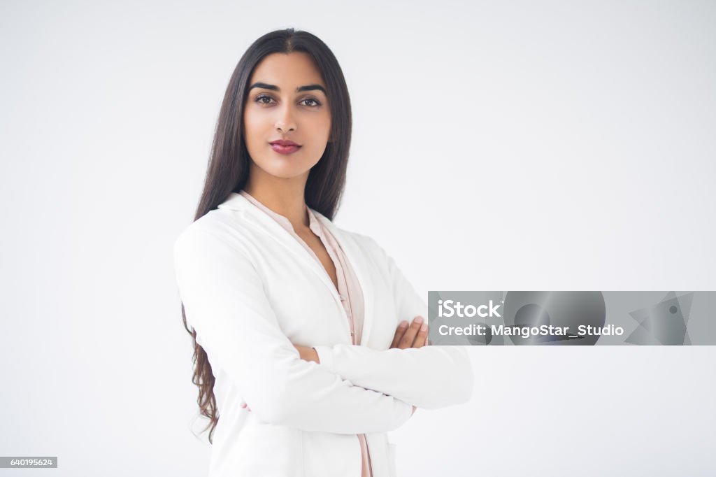 Closeup of Proud Gorgeous Indian Business Woman Closeup portrait of serious proud young gorgeous Indian business woman looking at camera and standing with arms crossed. Isolated view on white background. Women Stock Photo