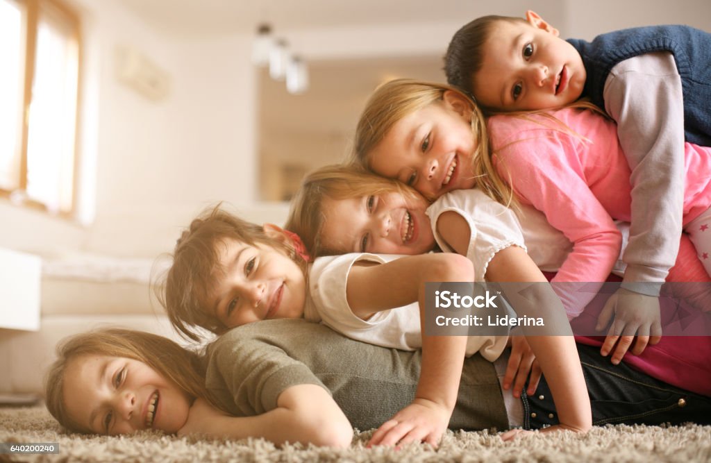 Children having fun at home. Large group of children lying at floor and having fun. Looking at camera. Brother Stock Photo