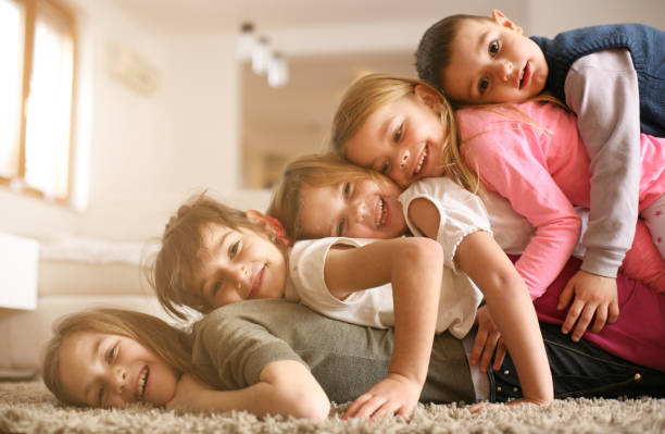 Children having fun at home. Large group of children lying at floor and having fun. Looking at camera. sibling stock pictures, royalty-free photos & images