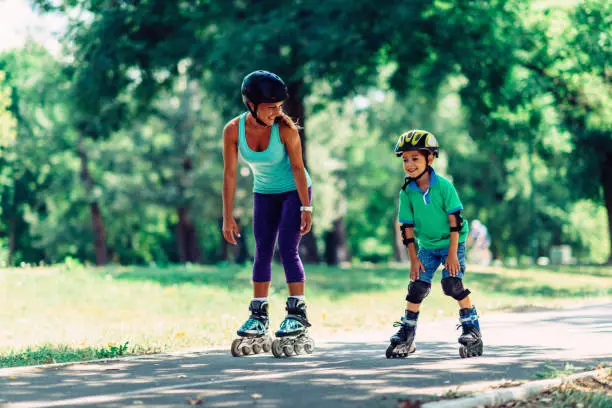 Photo of Mother and son roller skating in park