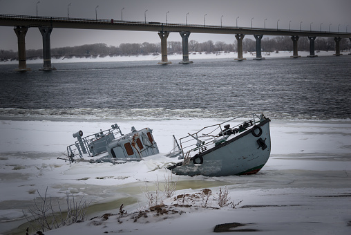 Sinking vessel in a frozen river covered with ice