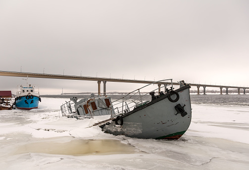 Boat wreck in a frozen river covered with ice