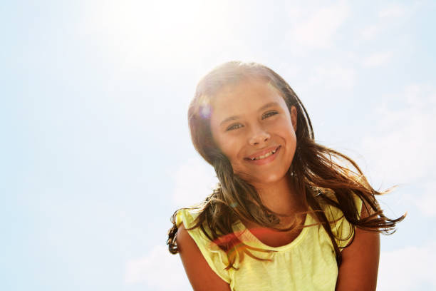 Portrait of a happy girl standing outside on a bright summer’s day