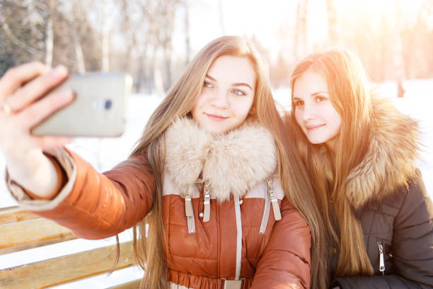istock Two smiling girls make selfie in winter park 640203720