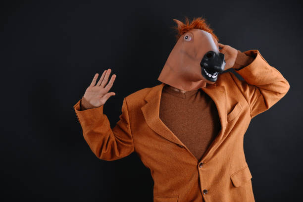 istock Man in orange jacket wearing a horse mask 640204522