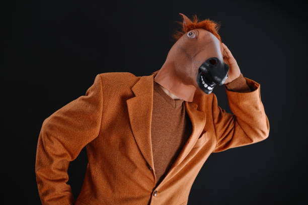 istock Man in orange jacket wearing a horse mask 640204864