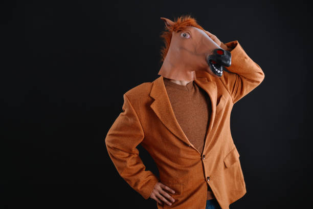 istock Man in orange jacket wearing a horse mask 640205150