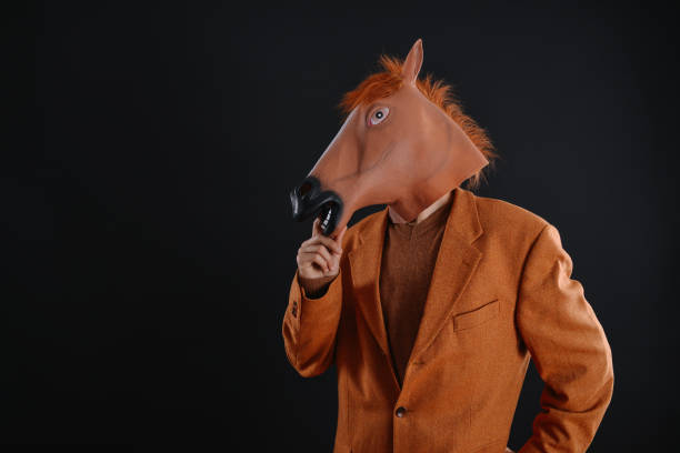 istock Man in orange jacket wearing a horse mask 640205420