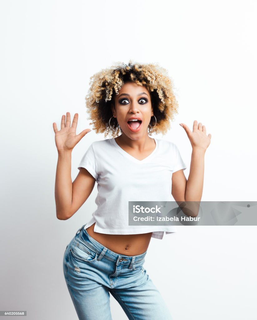 Surprised afro american young woman Surprised afro american young woman staring at the camera. Studio shot, white background. Ecstatic Stock Photo
