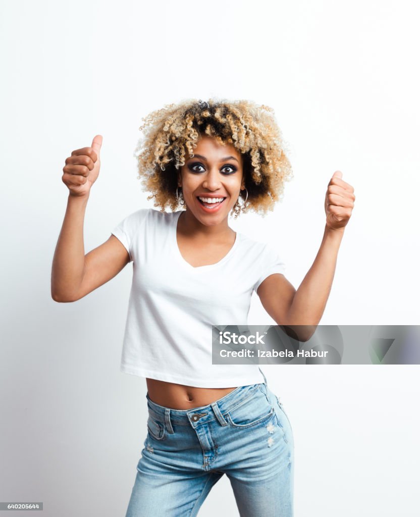 Excited afro american young woman Excited afro american young woman laughing at the camera with thumbs up. Studio shot, white background. Adult Stock Photo