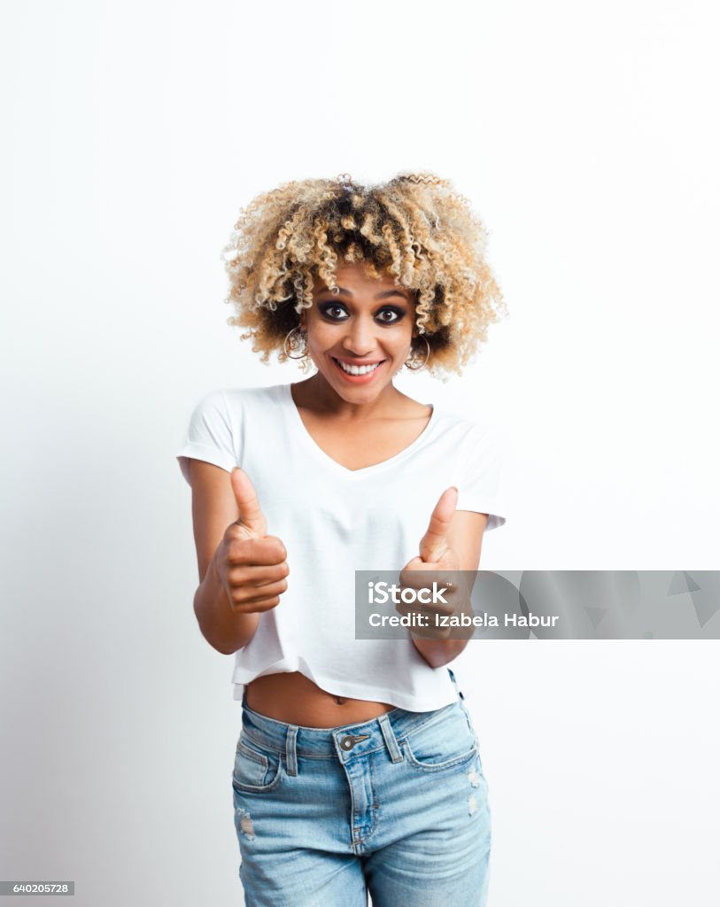 Successful afro american young woman Excited afro american young woman laughing at the camera with thumbs up. Studio shot, white background. African Ethnicity Stock Photo