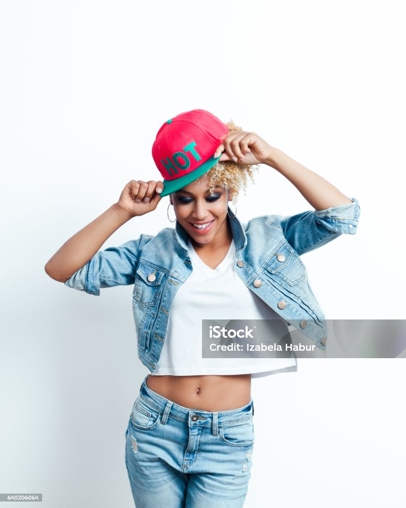 Happy afro american young woman Excited afro american young woman wearing denim jacket and baseball cap. Studio shot. Adult Stock Photo