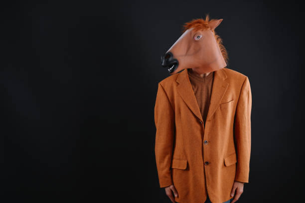 istock Man in orange jacket wearing a horse mask 640206264
