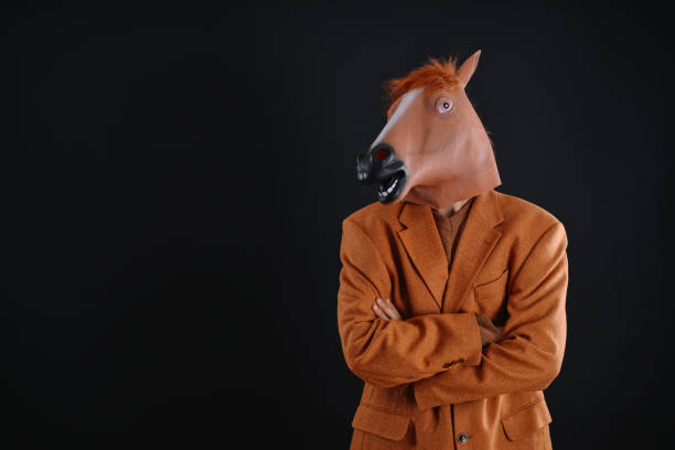 istock Man in orange jacket wearing a horse mask 640206986