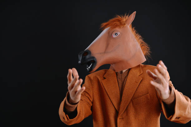 istock Man in orange jacket wearing a horse mask 640207342