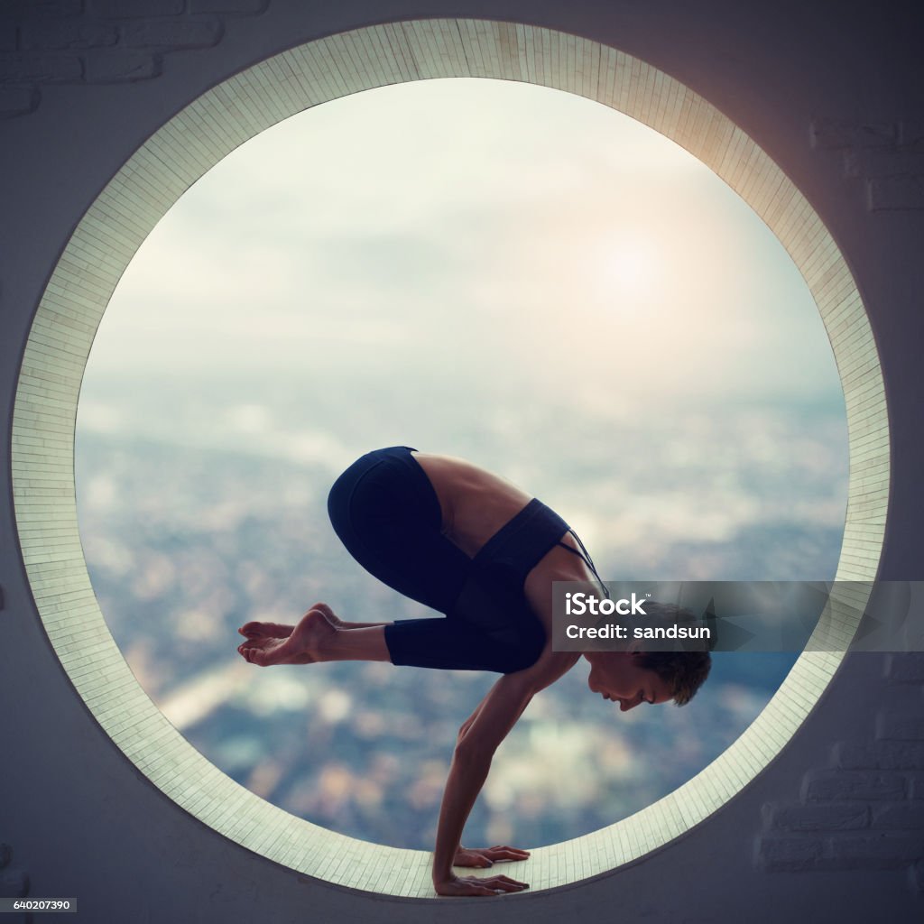 young woman doing yoga young woman doing bakasana in the round window Circle Stock Photo