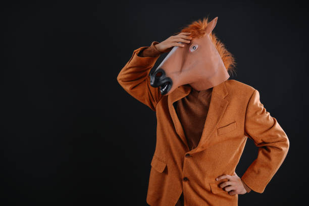 istock Man in orange jacket wearing a horse mask 640207568