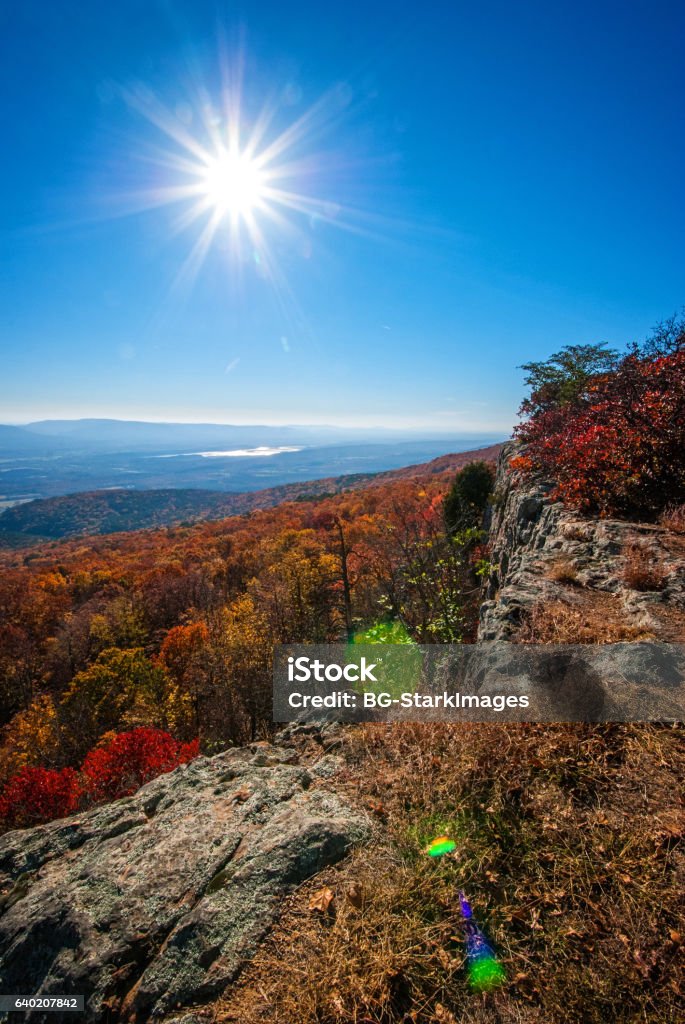 Hills Ablaze with Autumn Color View of vibrant fall colors with valleys,hills and lake in background. along with evening  sun and starburst. Autumn Stock Photo