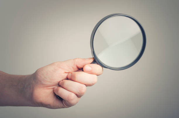 istock Hand holding a magnifying glass with blank background. 640208368