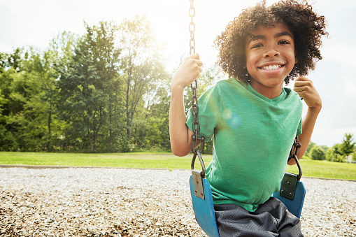 Portrait of a young boy playing on a swing at the park